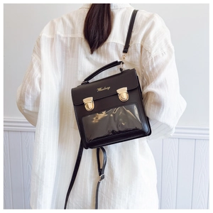 Detail of black PU leather ita bag with clear PVC window and gold buckle on a model