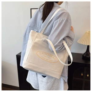 Detailed view of cream canvas tote bag showing side pockets and thick fabric texture