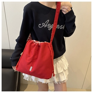 Détail du sac seau en toile rouge avec fermeture par cordon et étiquette mode