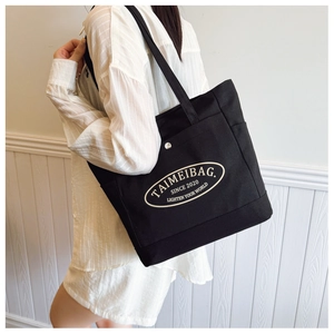 Macro view of a black canvas tote bag showing the sturdy fabric texture and printed logo