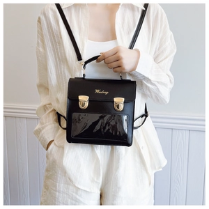Detail of black ita bag with clear window, gold buckles, and brand logo on PU leather
