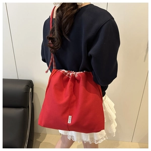 Détail du sac cabas en toile rouge avec doublure à carreaux et étiquette mode