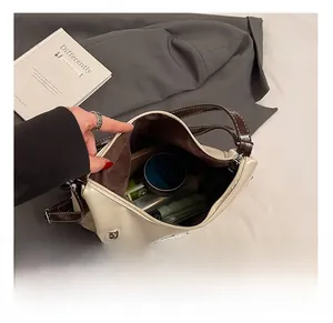 Vue macro de l'intérieur du sac à bandoulière en cuir crème montrant sa capacité réelle