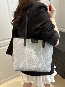 Grand sac cabas froissé argenté avec anses noires porté par un mannequin en blazer