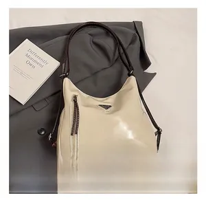 Détail d'un sac cabas crème en cuir ciré avec logo triangulaire en métal et fermeture