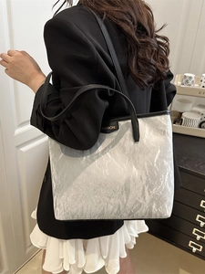 Sac cabas argenté froissé avec lanières noires et étiquette de mode, vue latérale chic