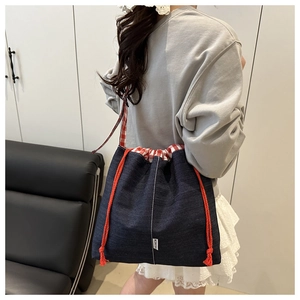 Détail du sac cabas en toile marine avec cordon rouge et bandoulière à carreaux rouges