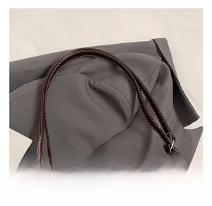 Détail de la bandoulière en cuir avec coutures blanches et zip argenté sur le sac