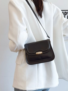 Borsa a tracolla classica in pelle nera con chiusura dorata indossata su blazer bianco