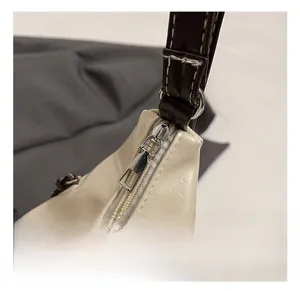 Gros plan détaillé du zip argenté et de la bandoulière marron du sac fourre-tout crème