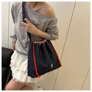 Détail d'un sac seau en denim avec cordon rouge et doublure à carreaux rouge et blanc
