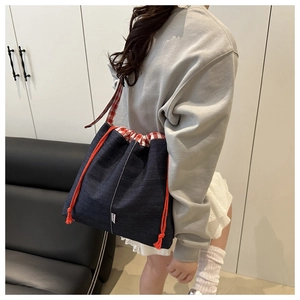 Détail du sac cabas en denim bleu avec doublure à carreaux rouges et étiquette