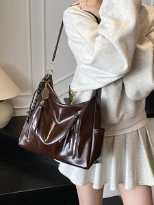 Brown polished leather hobo bag with parallel zippers and stylish scarf charm detail