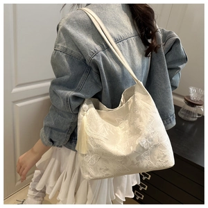 Close-up of white lace tote bag featuring exquisite butterfly embroidery and cream tassels