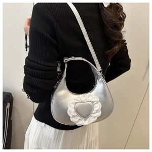 Close-up of silver crescent bag with heart lace patch and metallic leather texture