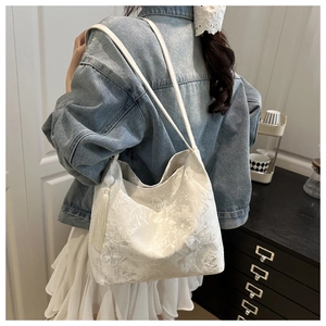 Detailed texture of white lace butterfly embroidery on a large stylish tote bag
