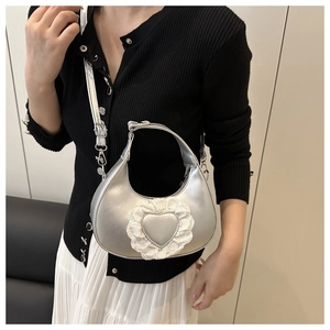 Close-up of silver hobo bag featuring lace heart detail and sleek metallic chain strap