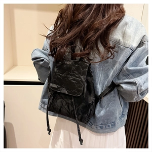 Close-up of black mini backpack with crinkled texture and flap drawstring closure