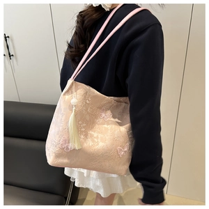 Détail du sac cabas rose brodé avec fleurs en dentelle, papillons et pompon blanc