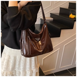 Détail du sac hobo marron foncé brillant avec logo triangulaire et zip latéral décoratif