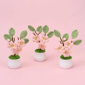 Plantes en pot de fleurs de pêcher crochetées à la main avec pétales roses et pots blancs