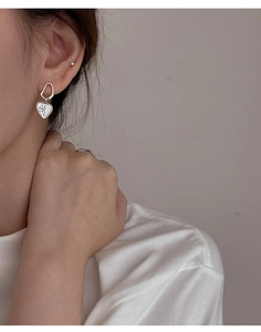 Detail view of S925 silver asymmetric heart earring with LOVE engraving on female model