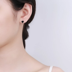 Macro shot of minimalist s925 silver heart hoop earring worn on model's ear