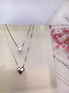 Collana a doppio strato in argento con cuore e ciondolo in zircone su sfondo sabbioso