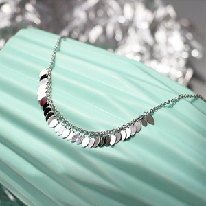 Silver leaf tassel anklet with elegant hanging charms on a soft textured background