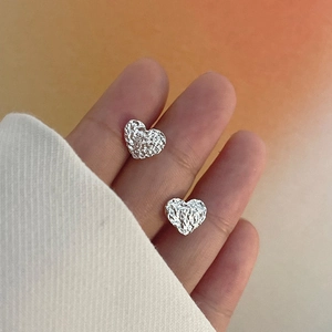 Détail de boucles d'oreilles cœur de lave argentées à texture métal froissé
