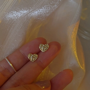Gros plan détaillé de boucles d'oreilles cœur dorées avec texture métallique martelée