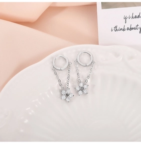 Macro detail of S925 silver flower chain drop earrings on a white ceramic tray