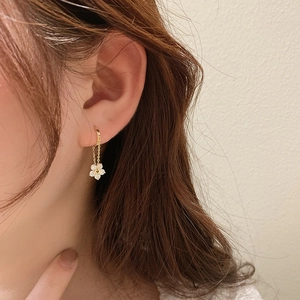 Detail of gold floral drop earrings featuring white zircon petals on delicate chains