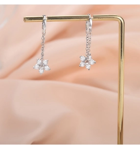 Macro detail of S925 silver flower drop earrings with zirconia on champagne silk backdrop