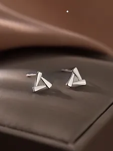 Makroaufnahme geometrischer S925 Sterlingsilber Dreieck-Ohrstecker auf Texturbasis