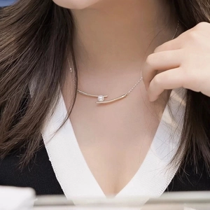 Minimalist gold necklace with a curved bar pendant and a round white pearl on model