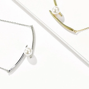 Macro detail of minimalist silver and gold pearl pendants on delicate cable chains