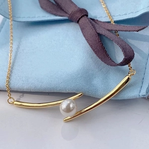 Detailed macro view of a gold curved bar pendant cradling a round white pearl