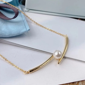 Elegant gold minimalist necklace featuring a round white pearl and curved metal pendant