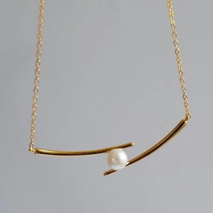 Minimalist gold necklace with geometric dual-arc pendant and white pearl center