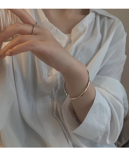 Silver Mobius wave bracelet and minimalist ring worn by model with glass cup