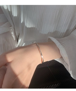 Detail of silver Mobius twist bracelet on wrist with elegant rippled fabric backdrop