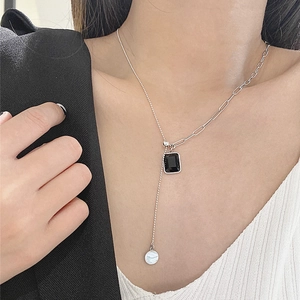 Detailed view of silver Y-shaped tassel necklace with black zircon square pendant on model