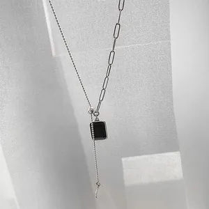 Macro detail of asymmetric silver chain necklace with black zircon rectangular pendant