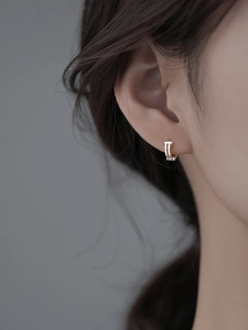 Macro shot of a double-layered S925 silver geometric hoop earring on a female model