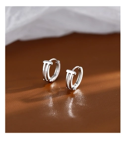 Macro detail of silver S925 earrings with T-shaped design on textured leather background