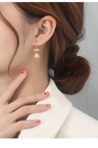 Close-up of golden bow earrings with cat eye stones worn by model showing elegant details