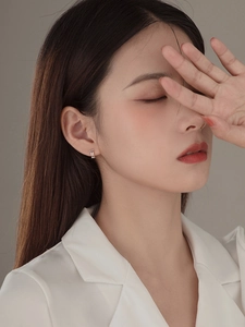 Detail of minimalist S925 silver double-layer hoop earrings worn by a model in white blazer