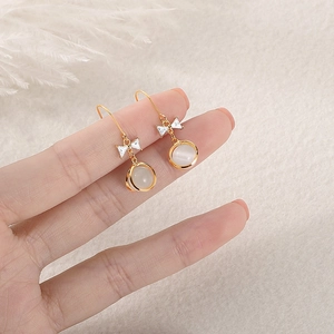 Elegant gold bow earrings with shimmering white cat-eye stone and zircon accents