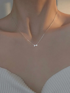 Close-up of elegant bow pendant necklace with micro-pave zircons on model's collarbone